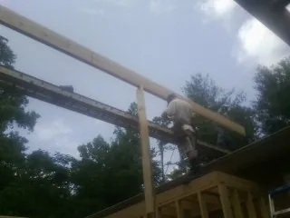 Carpenter setting a ridge beam over a new addition frame — Ice Dam Removal by Roofing Brothers in Rogers